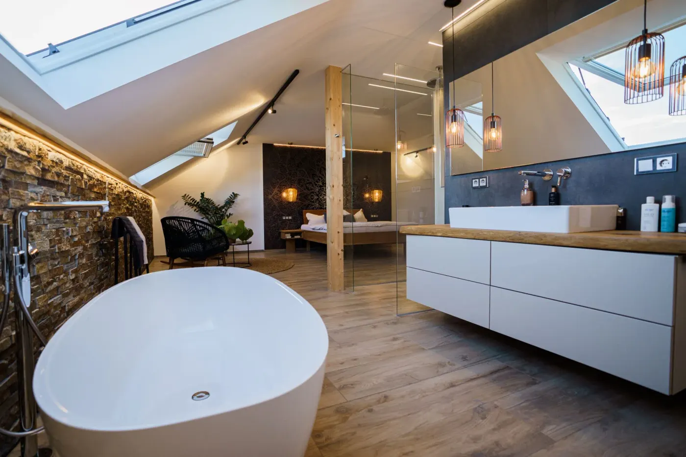 Dachgeschoss-Badezimmer mit freistehender Badewanne und Natursteinwand