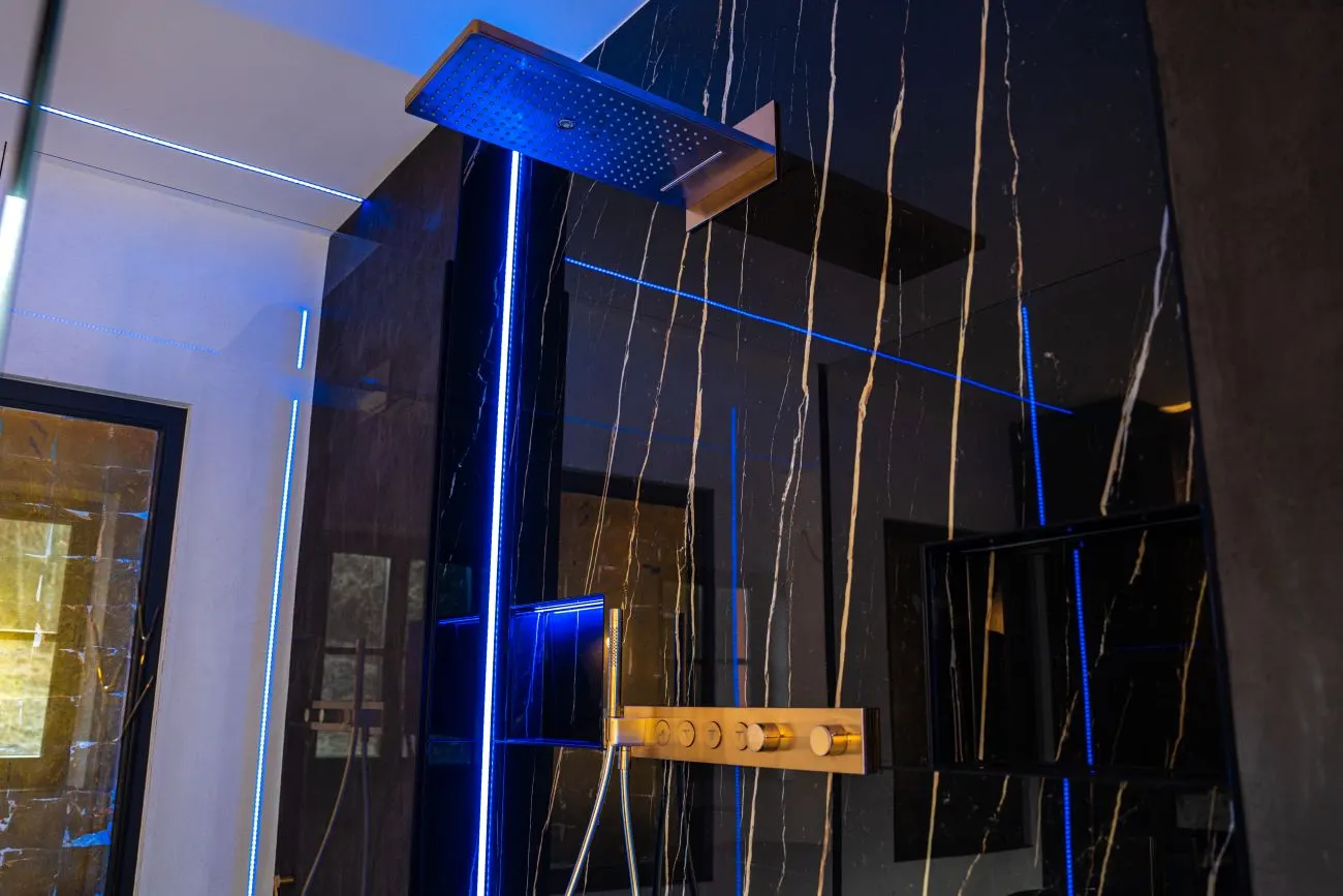 Schwarze Marmor-Dusche mit goldenen Armaturen und Regenduschkopf