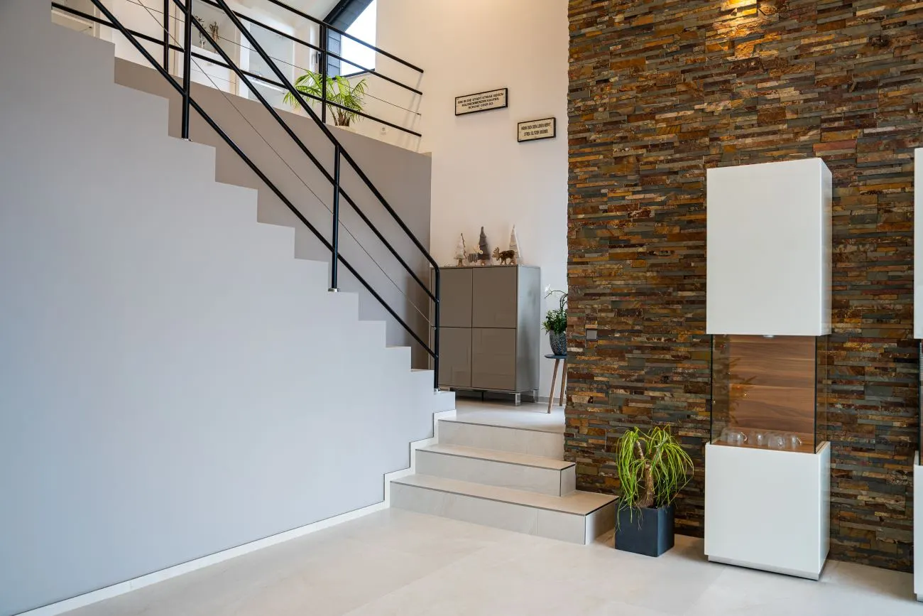 Eleganter Treppenaufgang mit Steinwand und stilvoller Dekoration